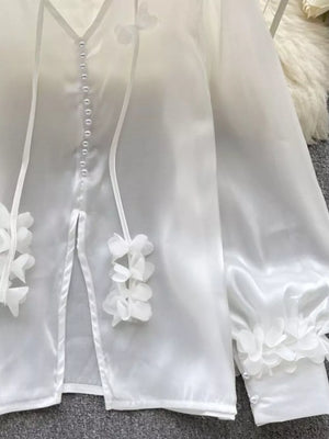 White sheer button-down shirt with delicate floral appliqué and pearl buttons.