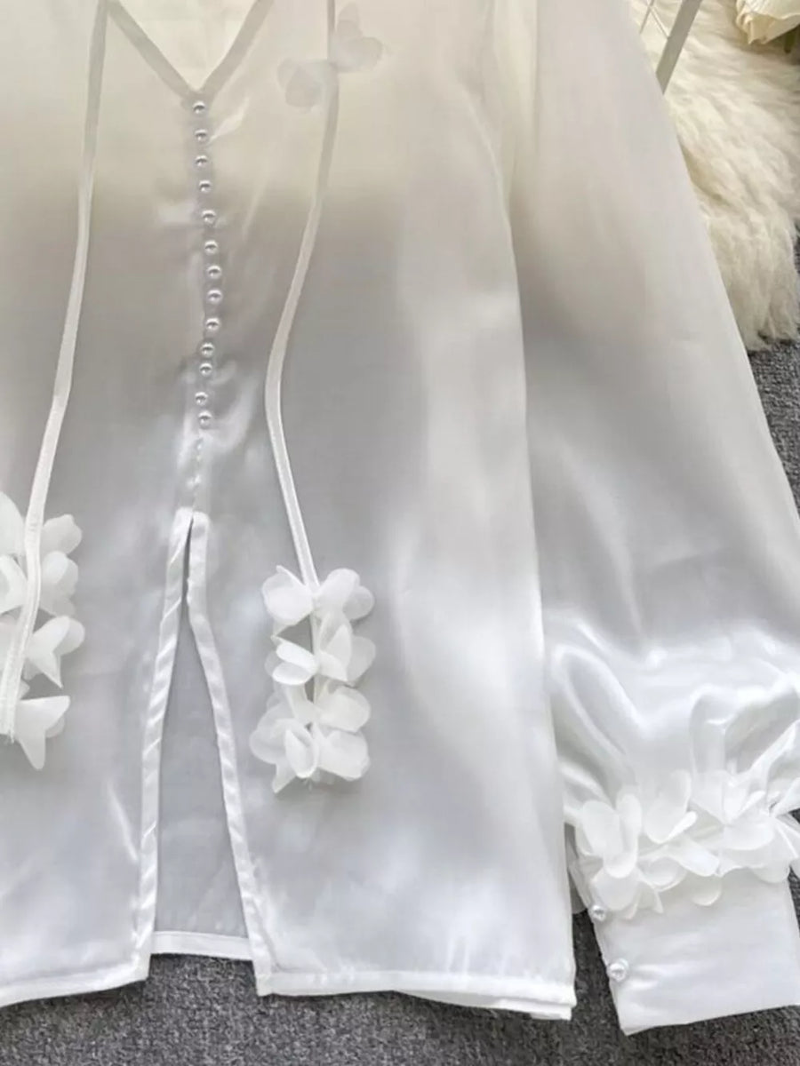 White sheer button-down shirt with delicate floral appliqué and pearl buttons.