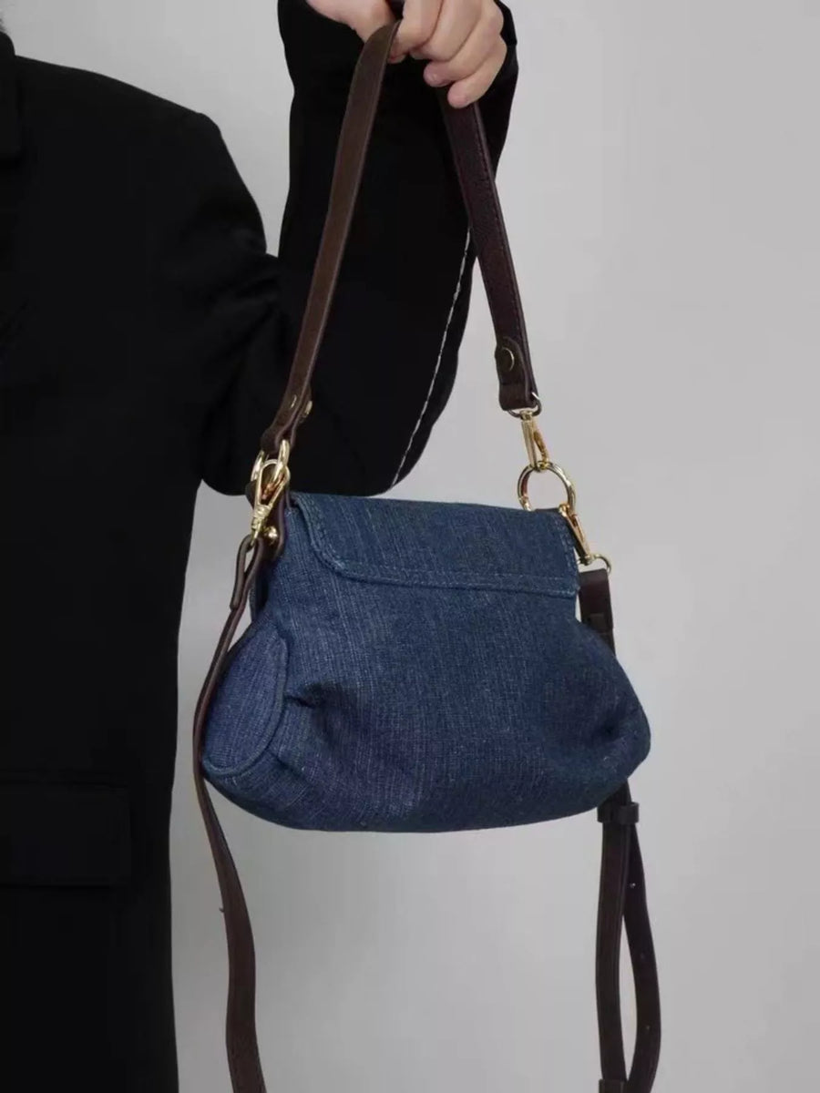 Mini denim shoulder bag with flap closure and brown leather straps.