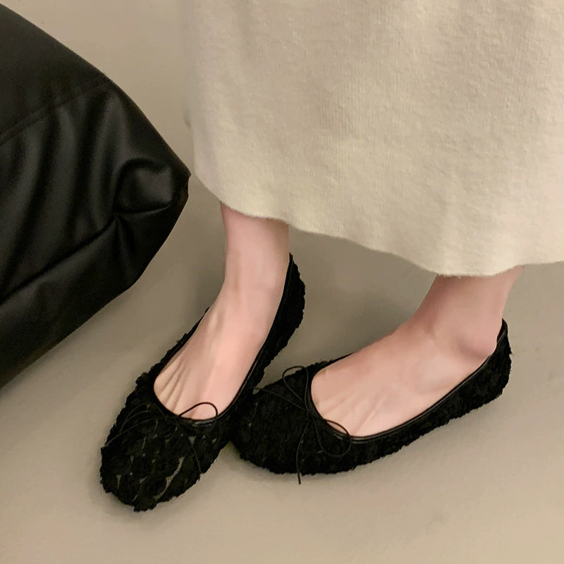 Black floral bow slip-on flats with 3D texture and a casual chic style.