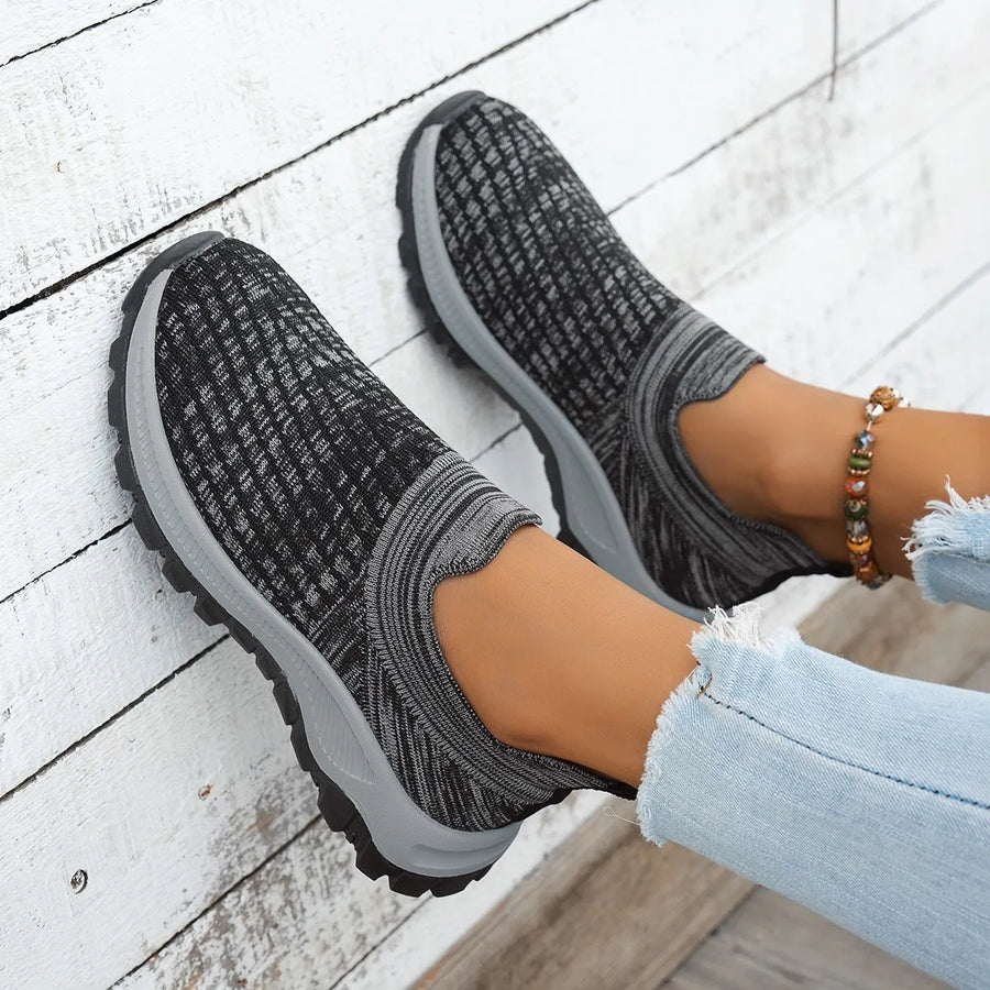 Textured knit slip-on sneakers in black with grey accents and a grey sole.