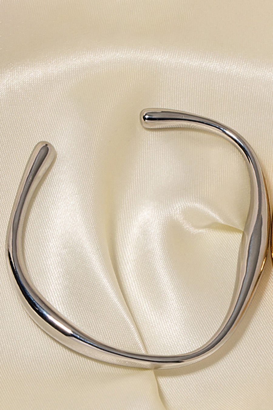 Sculpted silver open-ended bangle bracelet with a smooth, polished finish.