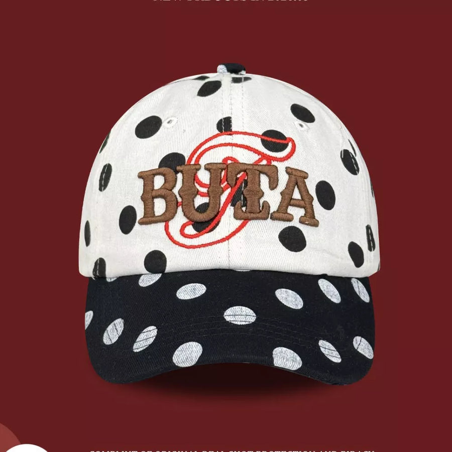 Baseball cap with white and black polka dots, embroidered "BUTA" text.