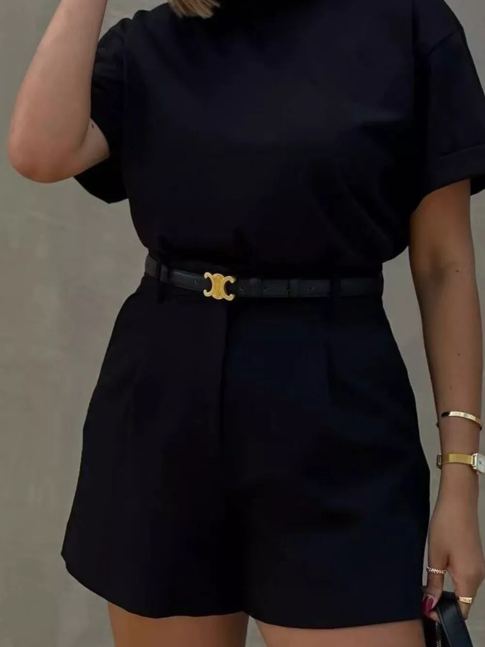 Black high-waisted shorts with pleats and a gold-buckle belt.