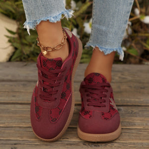 Red round toe lace up sneakers with all over pattern and brown sole.