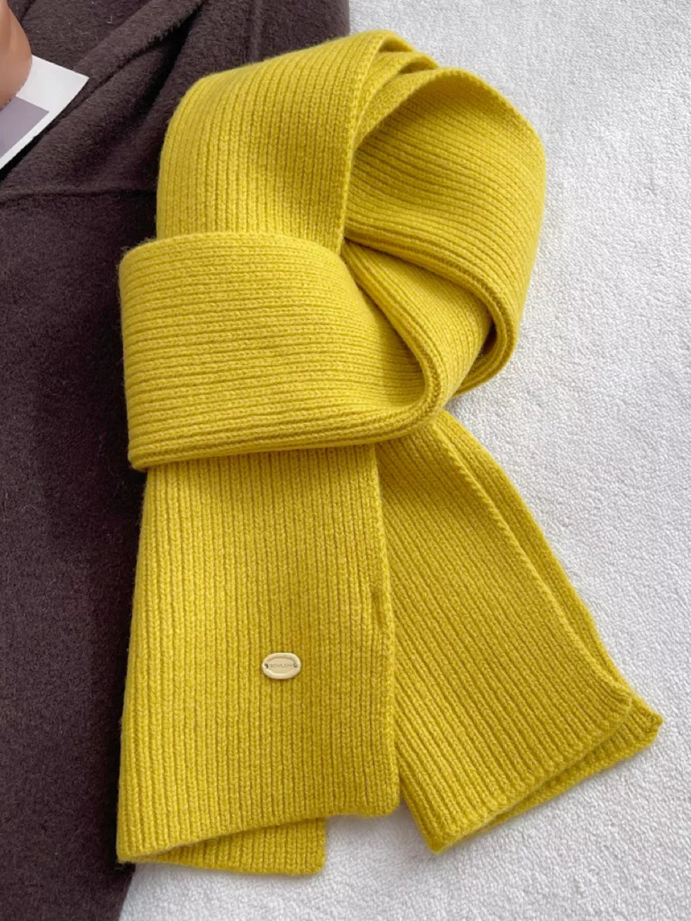 Yellow ribbed knit wool scarf with a small oval button detail.