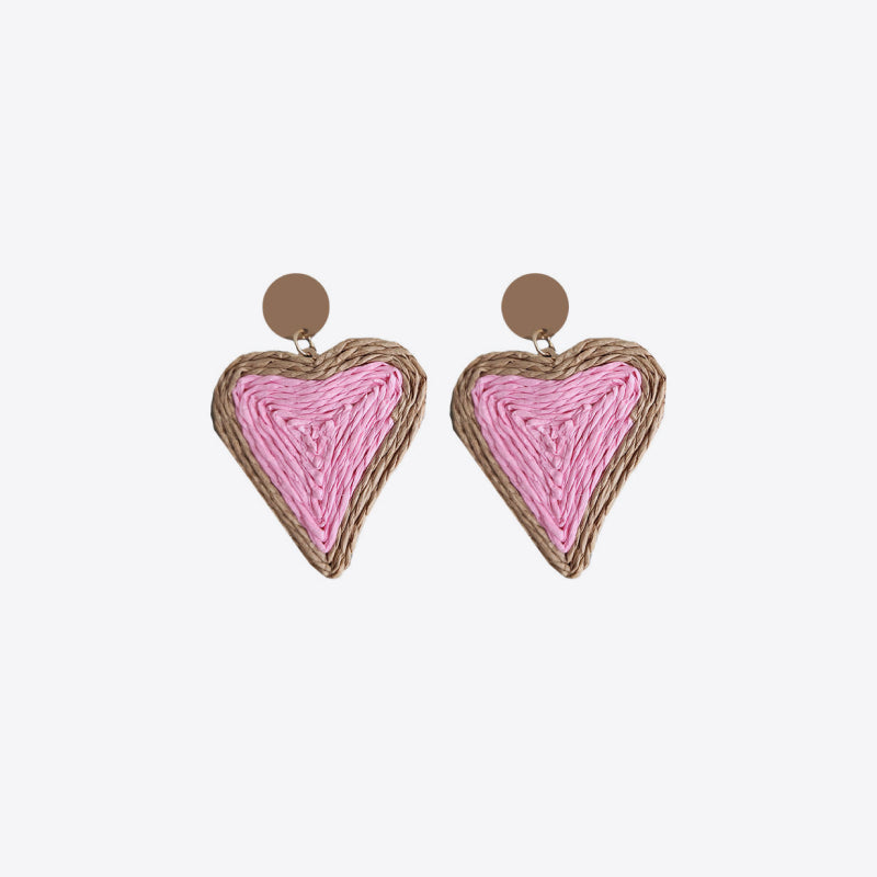 Pink woven heart statement earrings with natural raffia trim and brown stud backing.