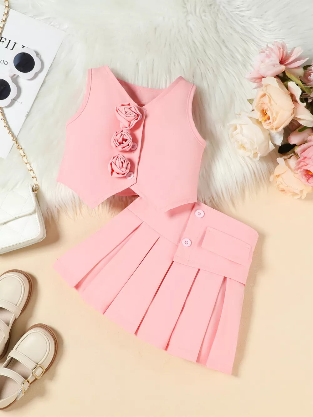 Pink floral vest and pleated skirt baby outfit with decorative buttons.