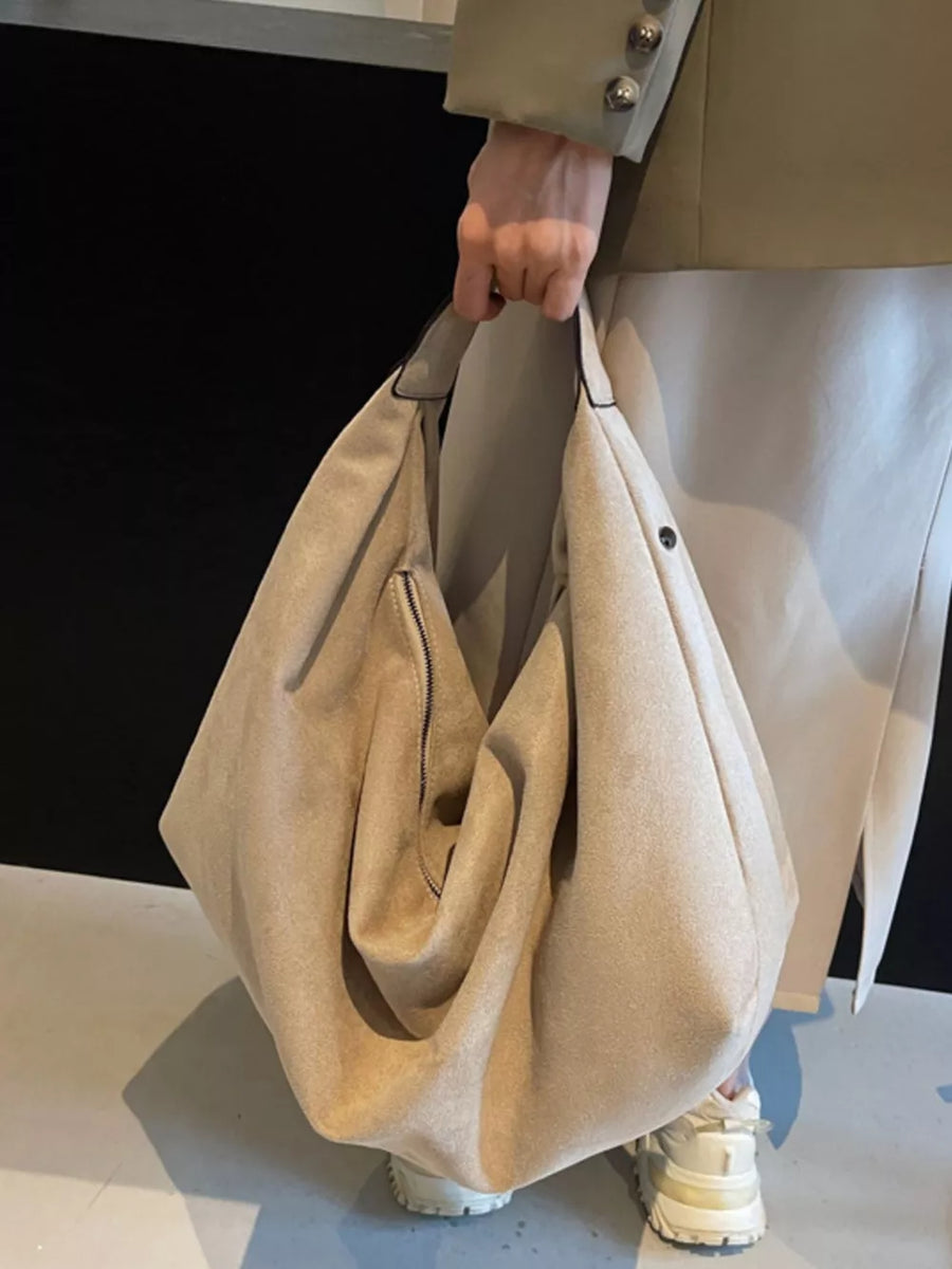 Spacious off-white suede shoulder bag with a front zipper pocket and top handles.