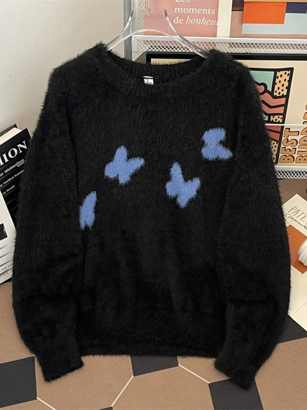 Black oversized fuzzy knit sweater with blue butterfly print and crew neck.
