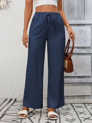 Navy blue high-waist wide-leg pants with drawstring detail and a relaxed fit.