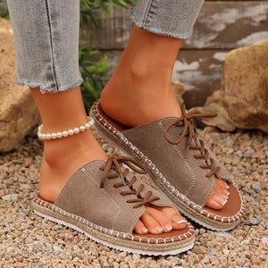 Khaki open-toe flats with lace-up detail and espadrille trim.