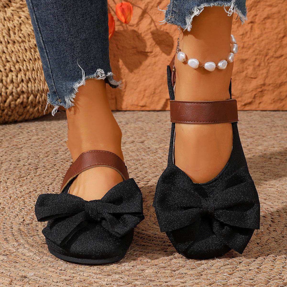 Black textured round toe flats with large bow detail and brown ankle strap.