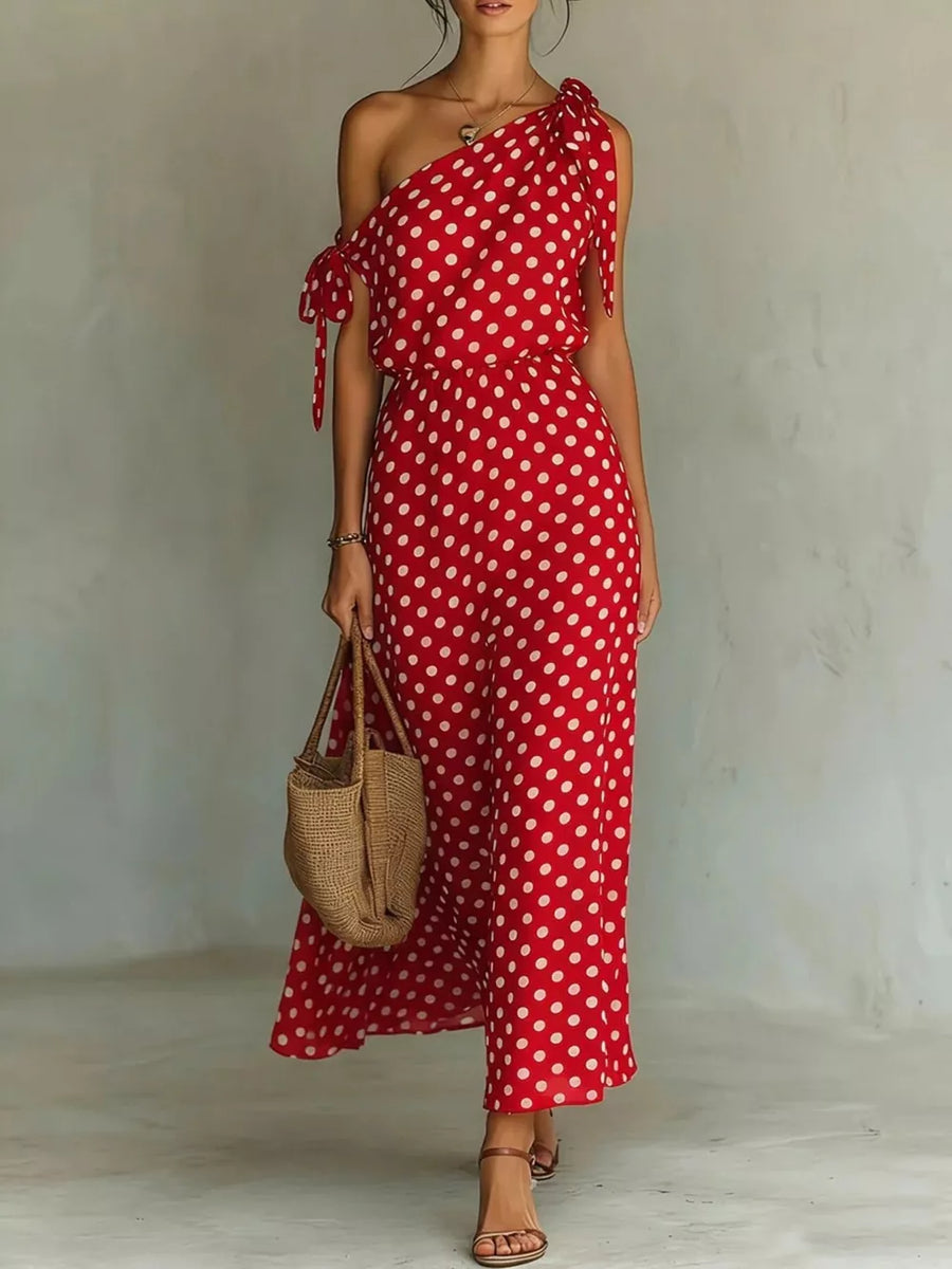 Red polka dot one-shoulder maxi dress with tie details and a cinched waist.