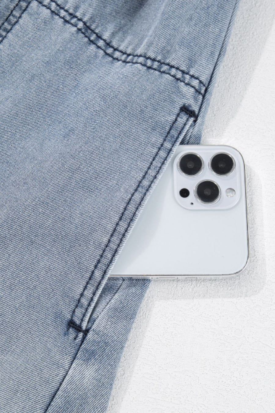 Gathered waist denim mini dress in medium wash with a phone in the pocket.