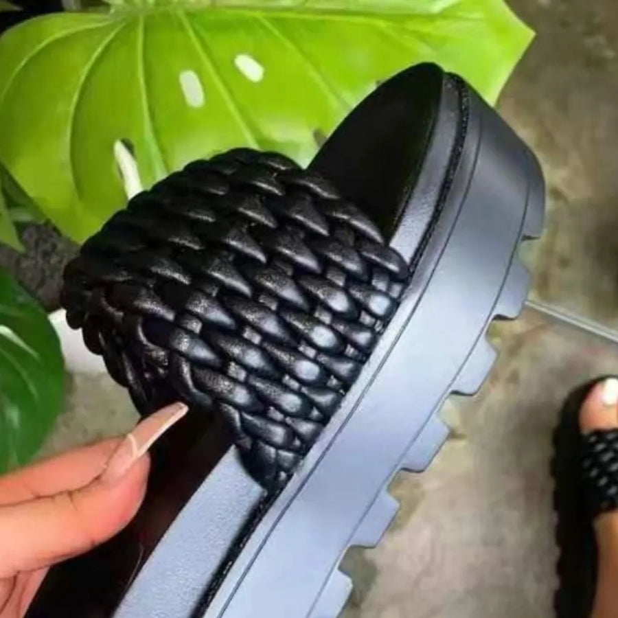 Black woven platform slide sandals with a chunky lug sole.