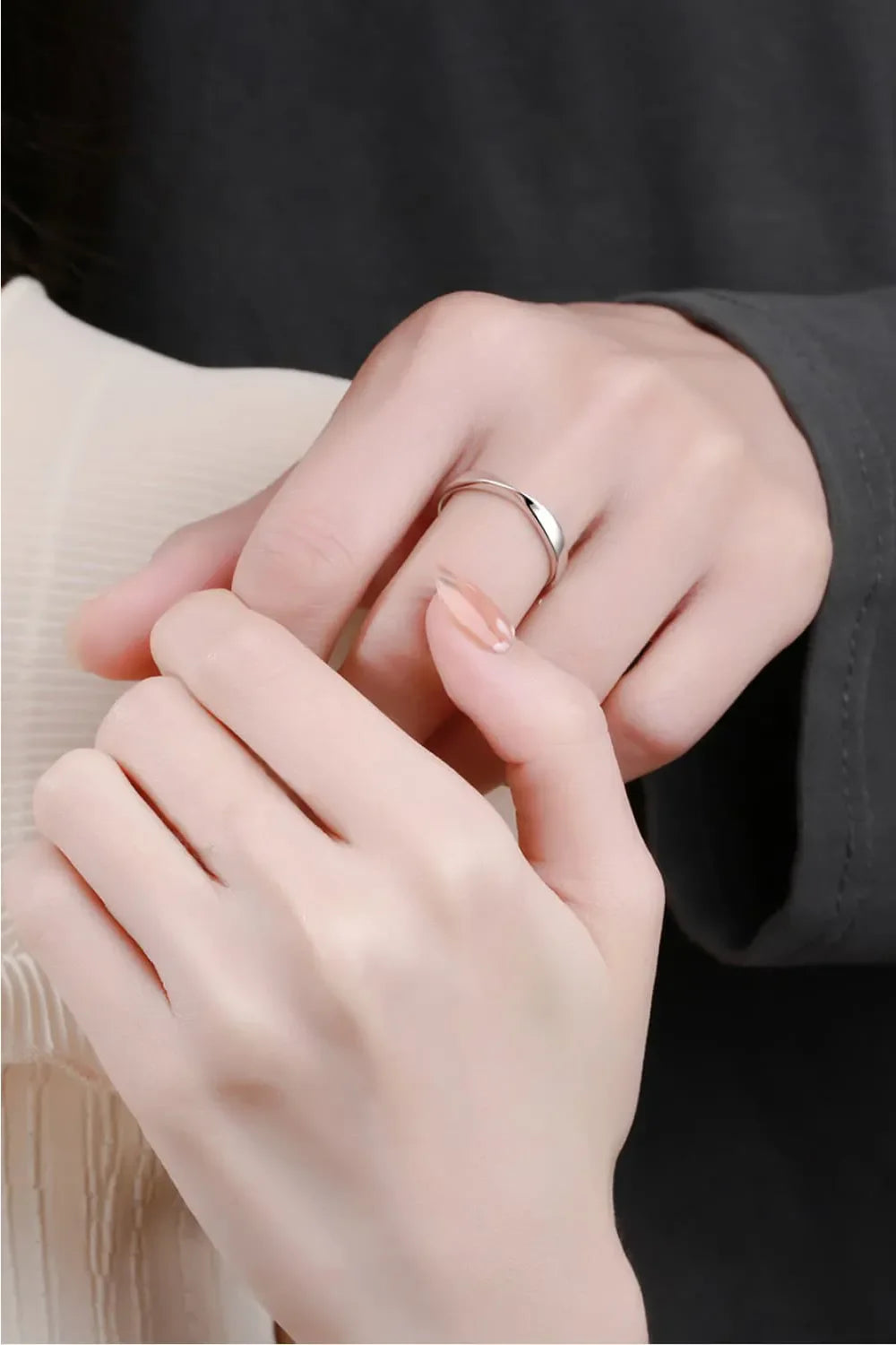 Delicate silver band ring with a subtle twist detail on a woman's finger.