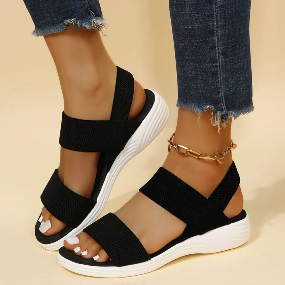 Black knit strap sandals with white soles and a gold chain anklet.