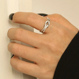 Silver knot ring with zirconia details on a hand.
