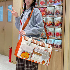 Charming gingham pattern travel bag with orange trim and cute bear applique.