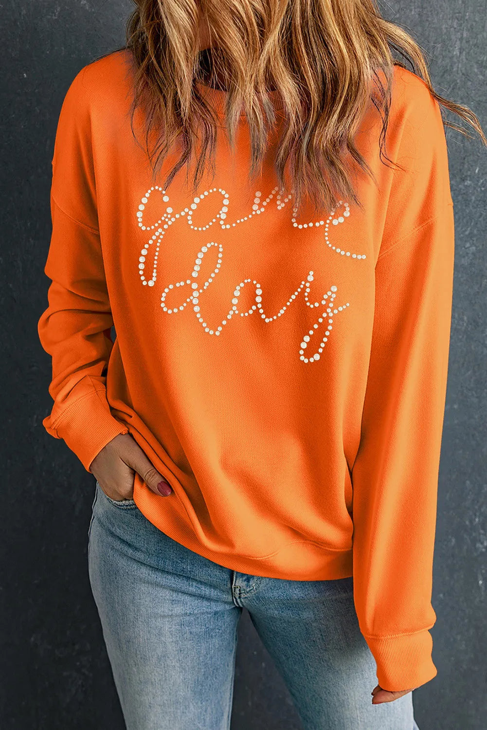 Orange crewneck sweatshirt with white pearl embellished "Game Day" graphic.