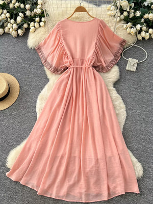 Pink embroidered V-neck bohemian maxi dress with flutter sleeves and a belted waist.