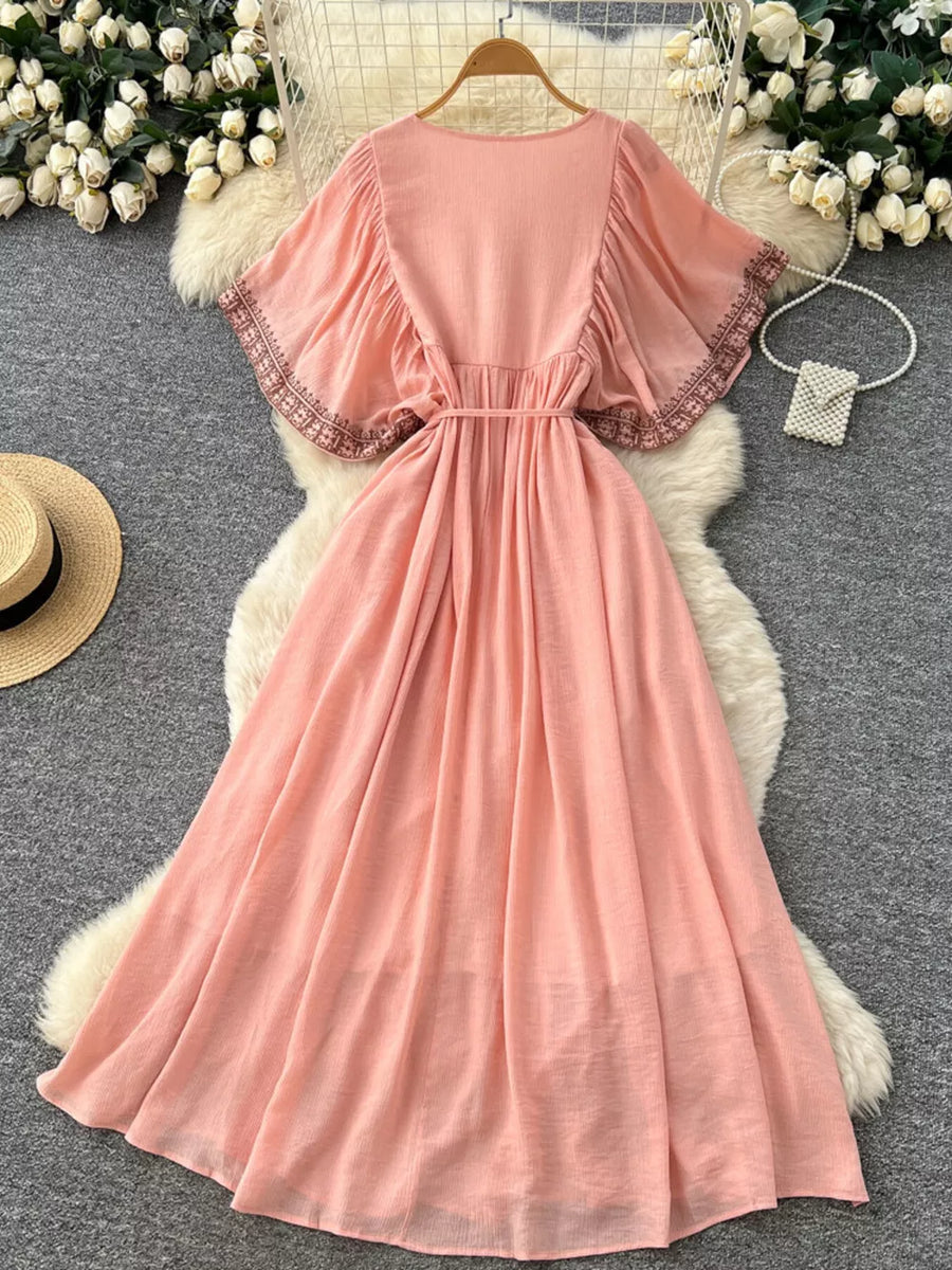 Pink embroidered V-neck bohemian maxi dress with flutter sleeves and a belted waist.