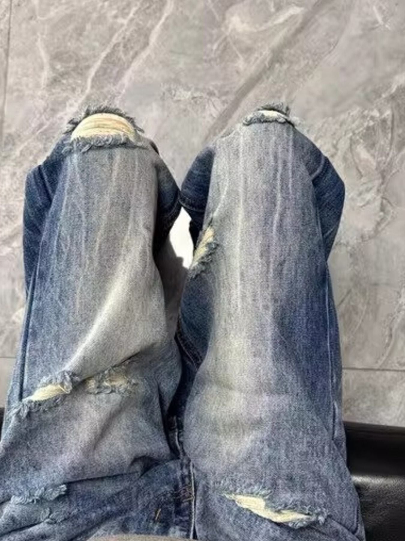 Men's blue distressed baggy jeans with visible pocket details and frayed hems.