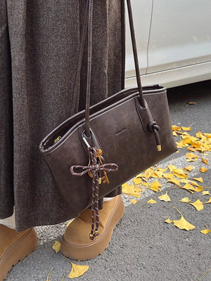 Brown leather shoulder bag with key charm and rope detail.