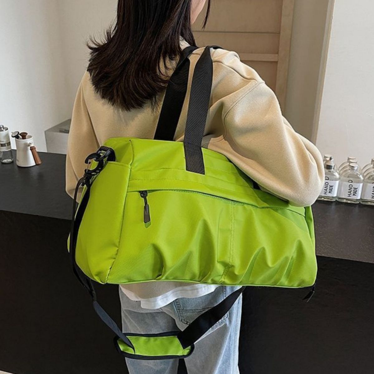 Green nylon travel duffel bag with black straps and multiple zippered pockets.