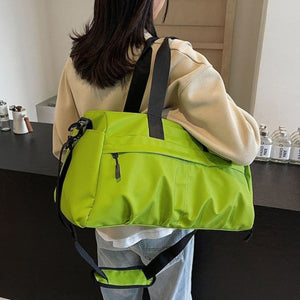 Green nylon travel duffel bag with black straps and multiple zippered pockets.
