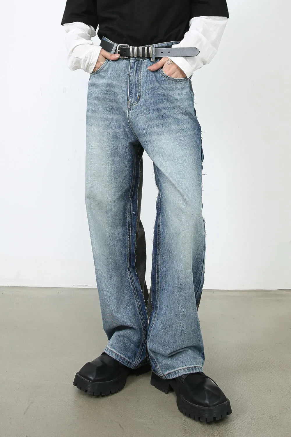 Paneled wide-leg denim trousers in medium wash with distressed details and a relaxed fit.