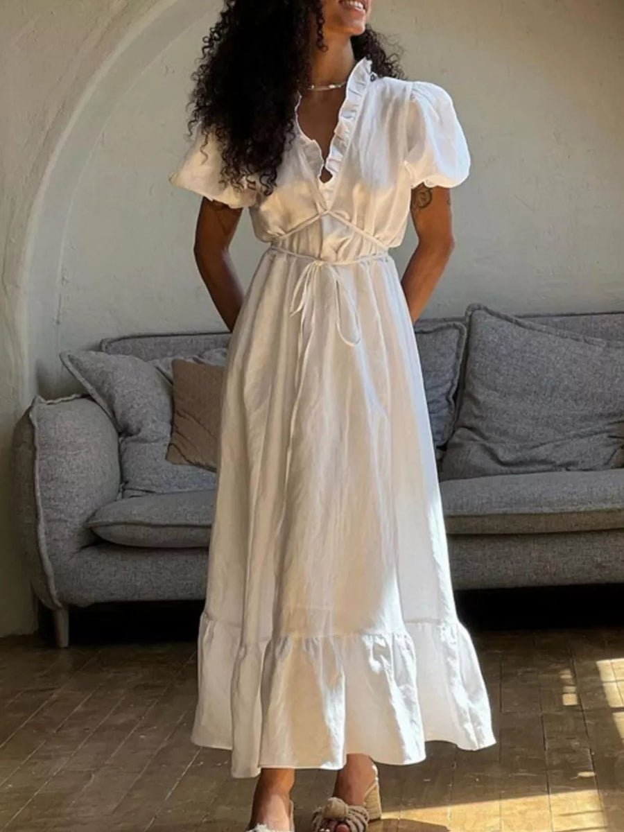 White linen midi dress with ruffled neckline, puff sleeves, tie waist, and tiered hem