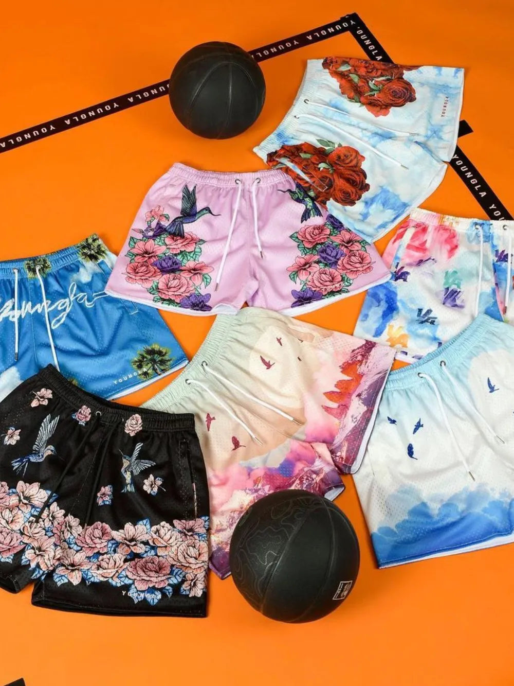 Mesh athletic shorts with floral and bird prints in black, pink, and blue.