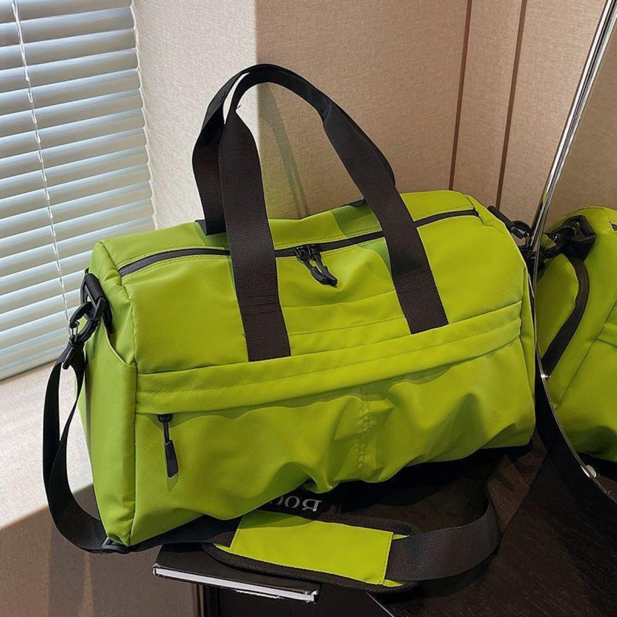 Green nylon travel duffel bag with black straps and multiple zippered pockets.