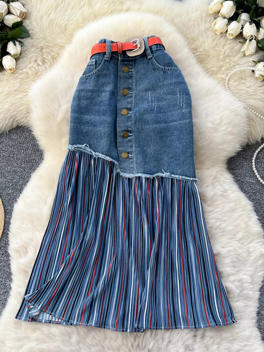 Patchwork denim midi skirt with button front, frayed hem, and pleated striped detail.