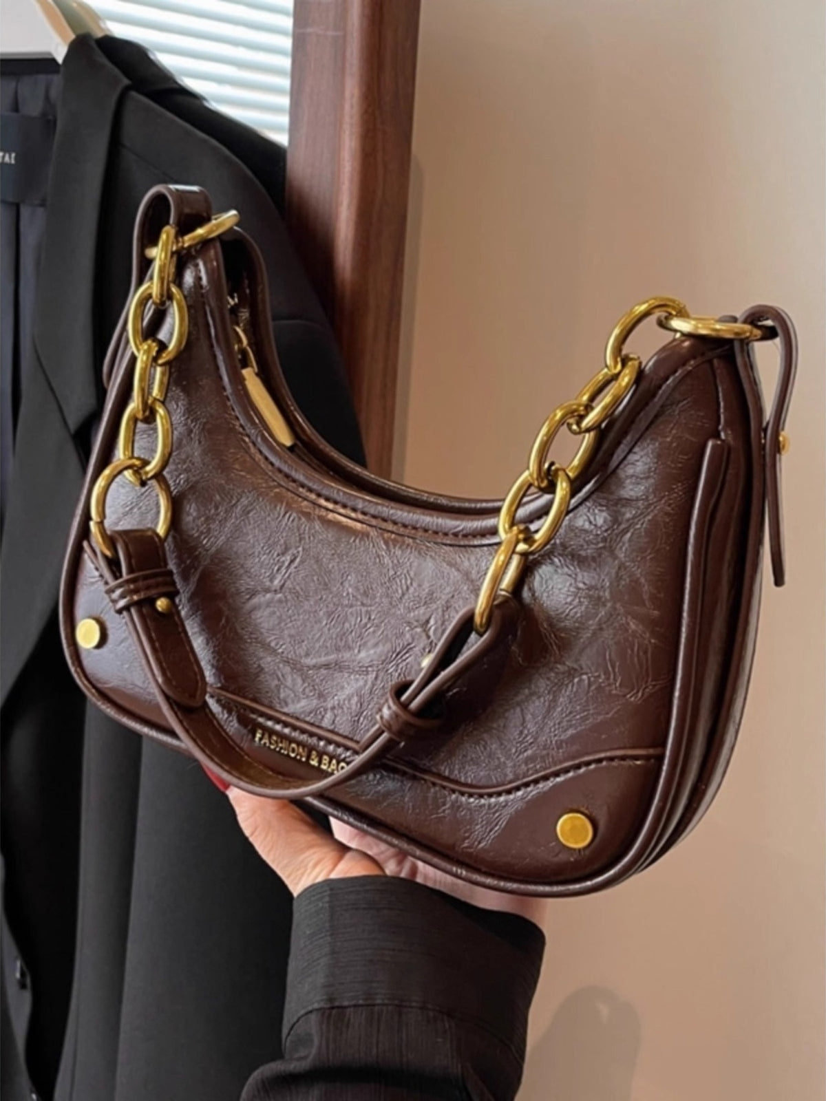 Coffee color crescent shoulder bag with chunky gold chain accent and embossed logo.