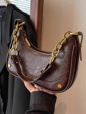 Coffee color crescent shoulder bag with chunky gold chain accent and embossed logo.