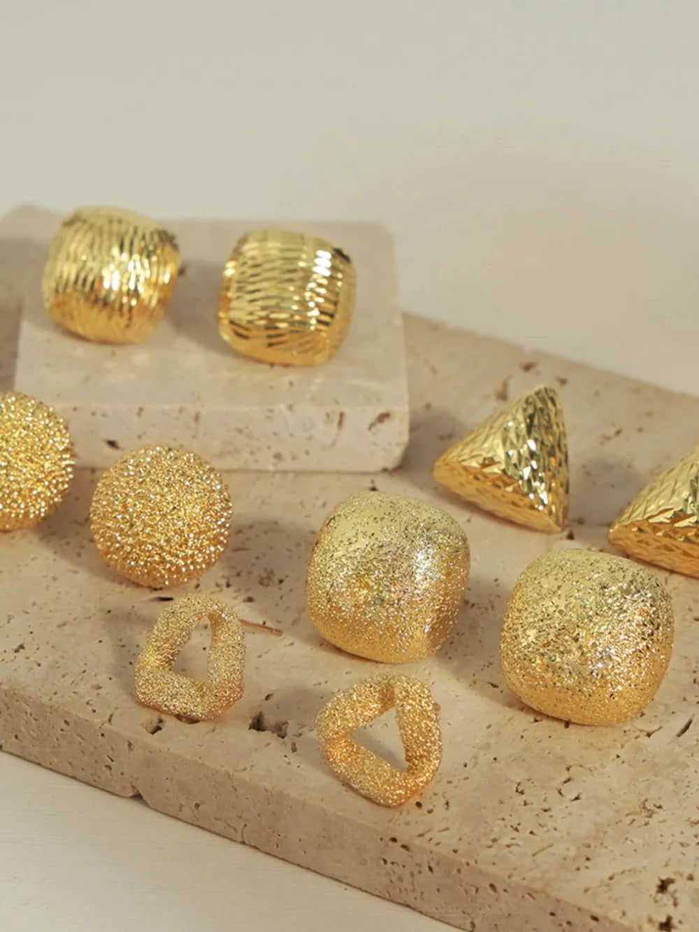 Textured gold cube earrings with various geometric shapes and glittery finishes.