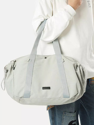 Light gray athletic nylon tote bag with racket holder and cinch cord closure.
