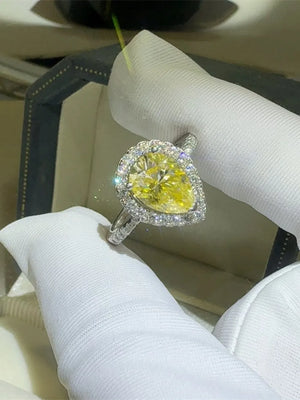 Yellow pear-cut moissanite ring with diamond halo and band.