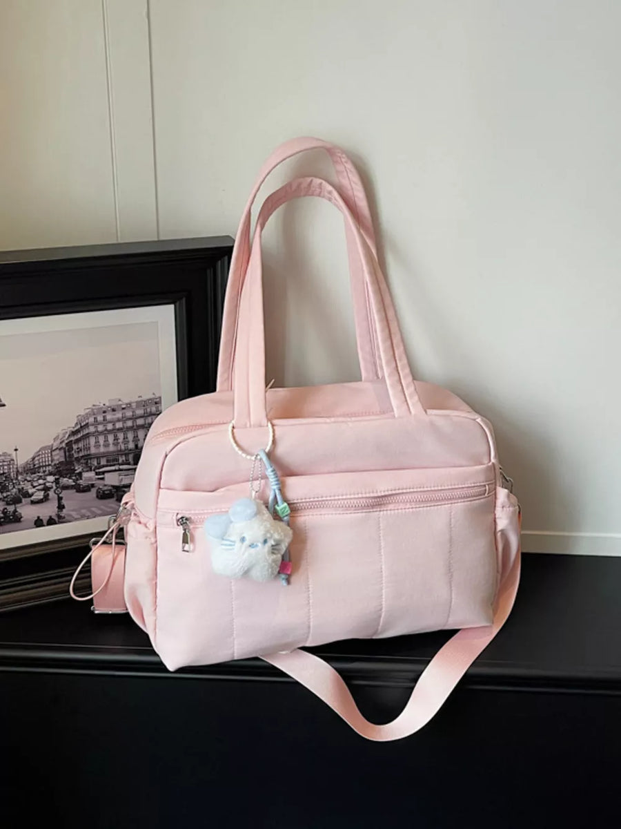 Pink quilted duffel bag with zip pockets and a fuzzy cloud charm