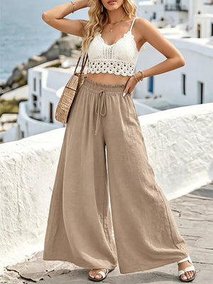 Wide leg linen pants in tan with drawstring waist and ruffled hem.