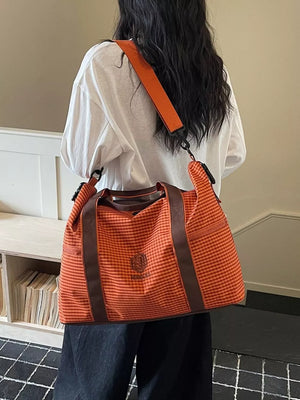 Large orange plaid travel bag with brown trim and adjustable shoulder strap.