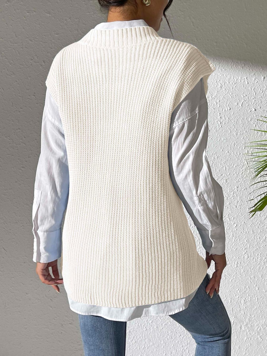 Ivory ribbed knit vest with mock neck, styled over a light blue button-down shirt.