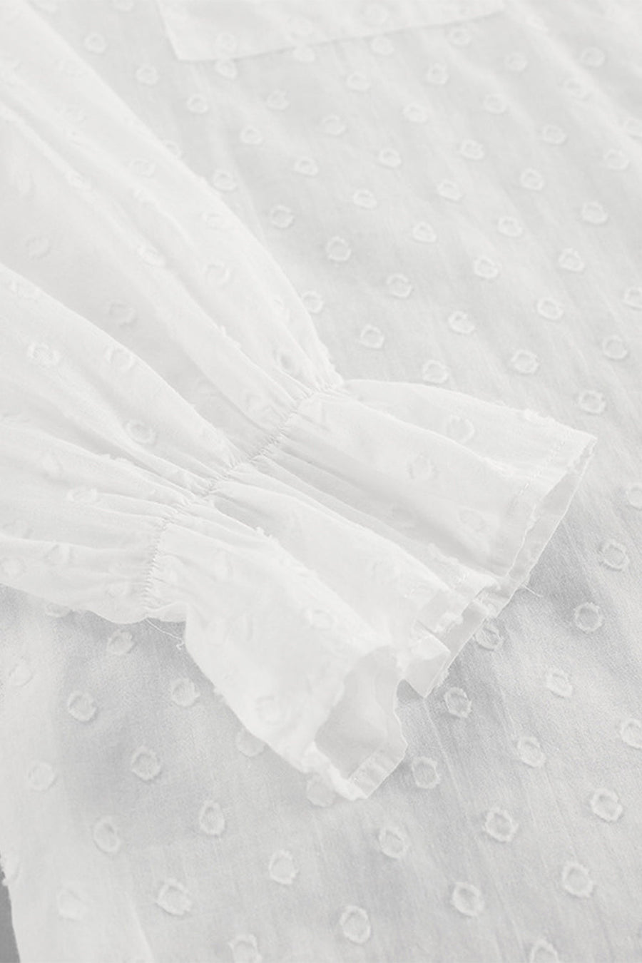 White textured ruffle trim shirt with gathered sleeves and a dotted pattern.