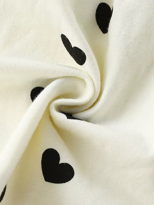 Children's ivory dress with black heart print and ruffle sleeve detail.