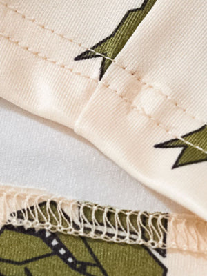 Toddler dinosaur print tee and shorts set in cream with green dinosaur pattern and stitched details.