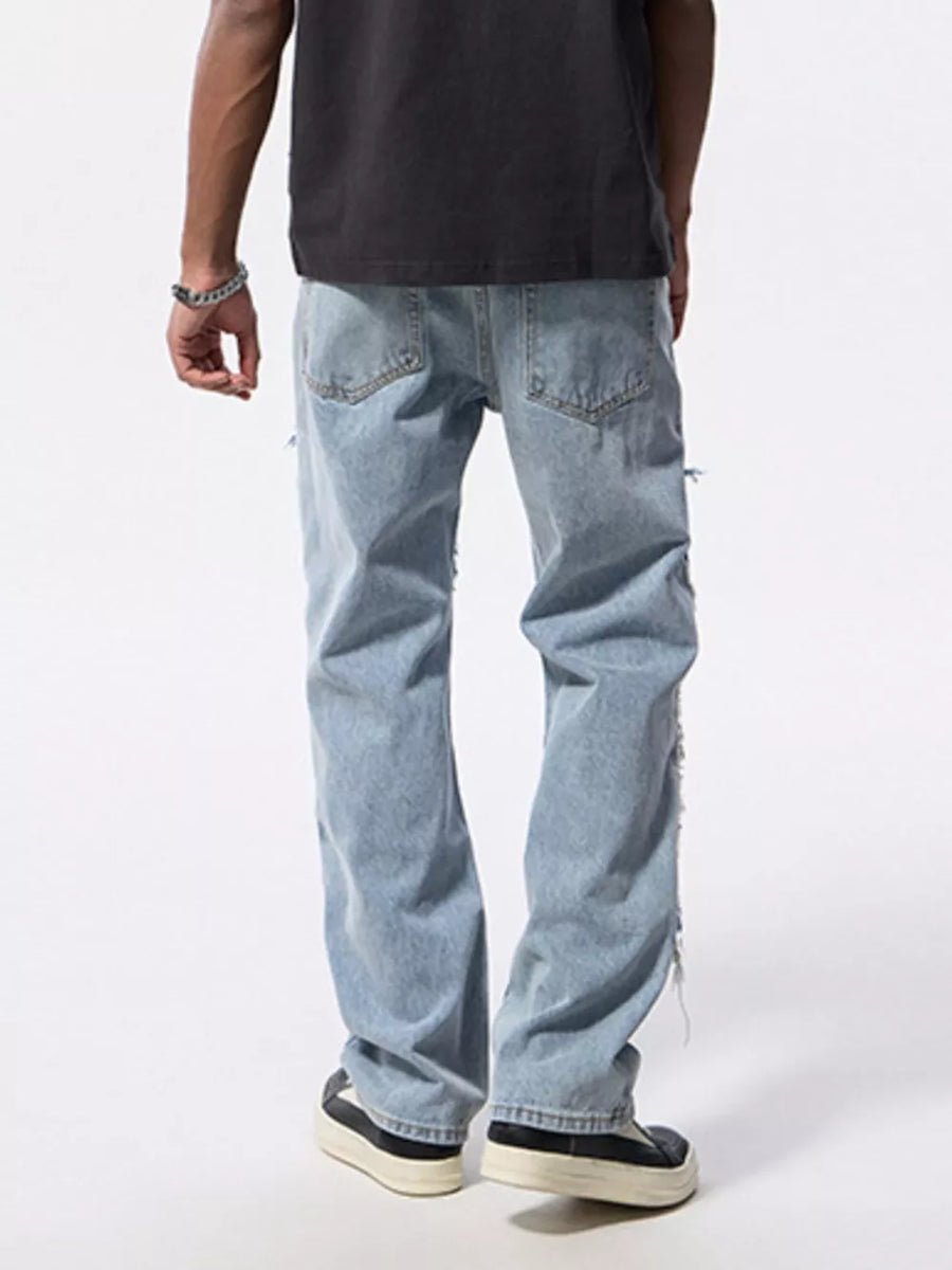Men's light wash distressed patchwork cotton jeans with ripped details.