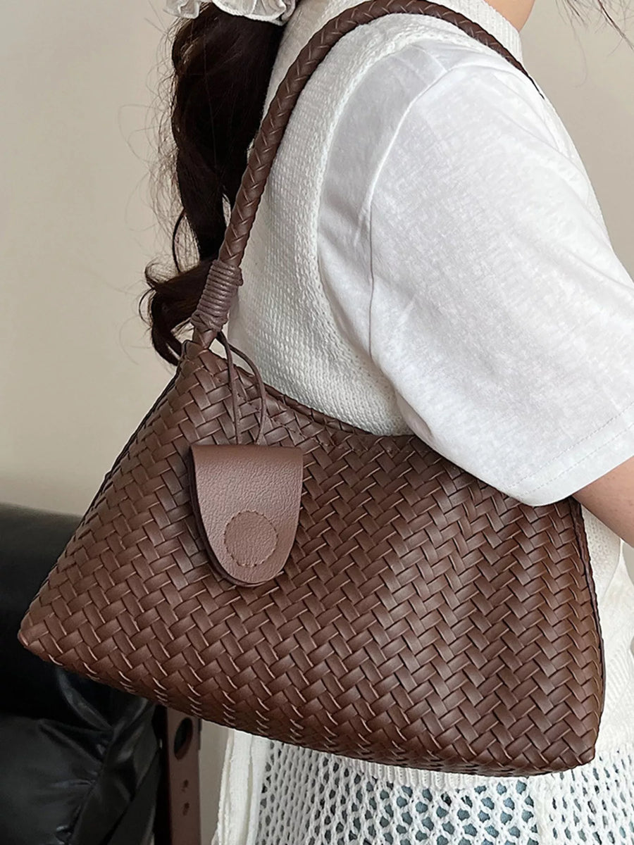 Woven shoulder bag in coffee color with braided strap and leather tab detail.